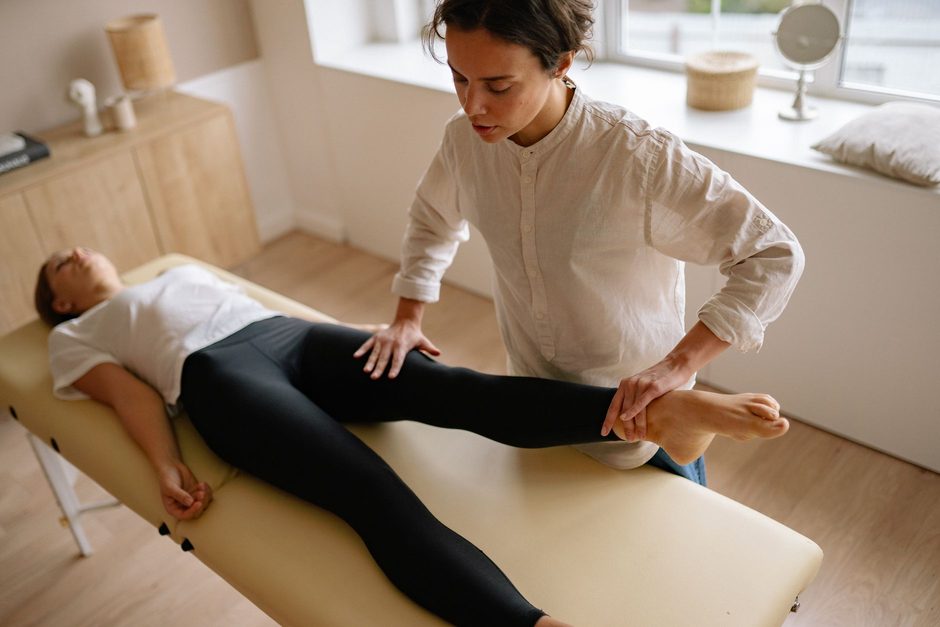 Physiotherapist treating a client’s leg in a bright treatment room